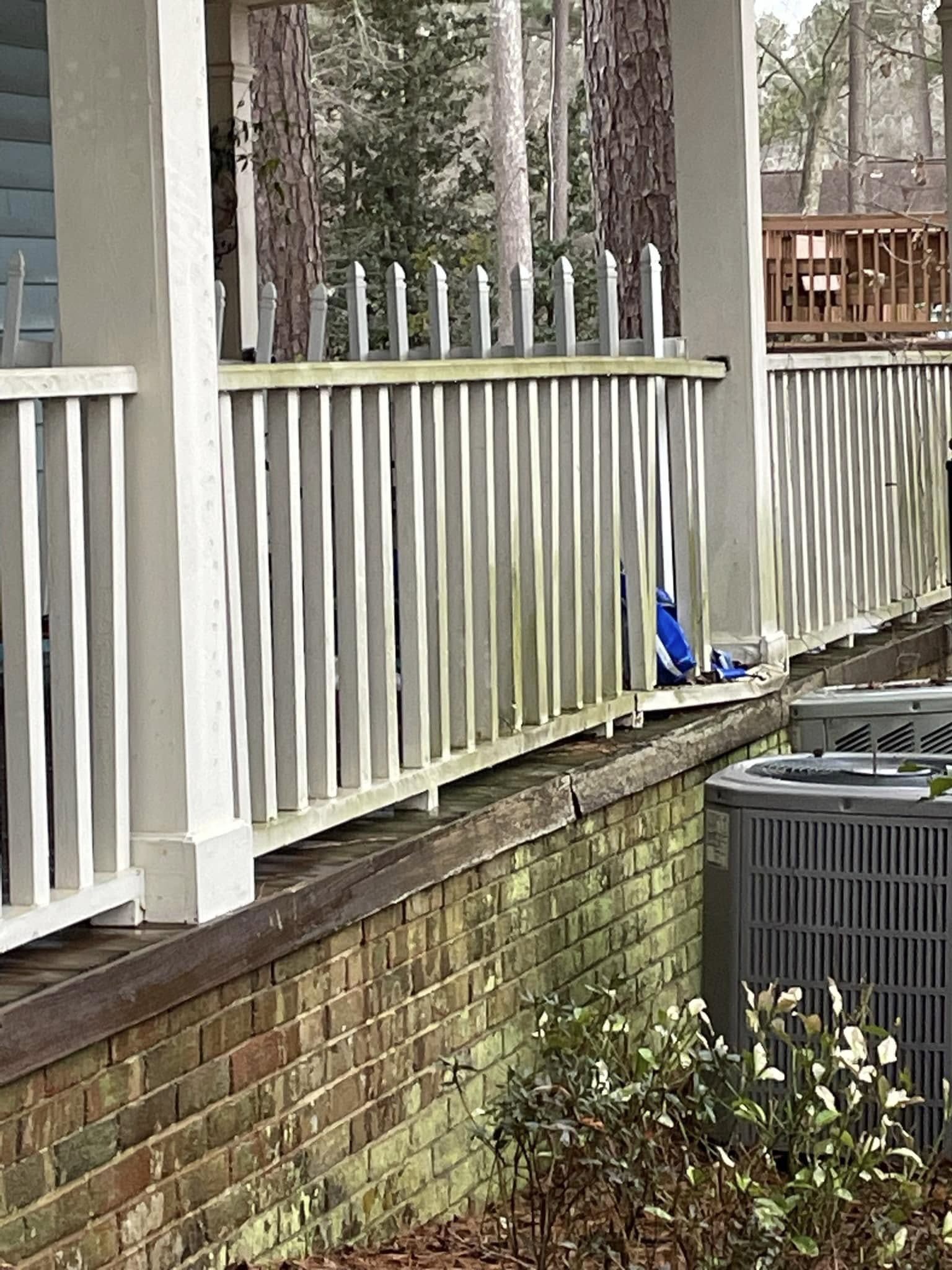 Brick wall and railing covered in green algae before pressure washing