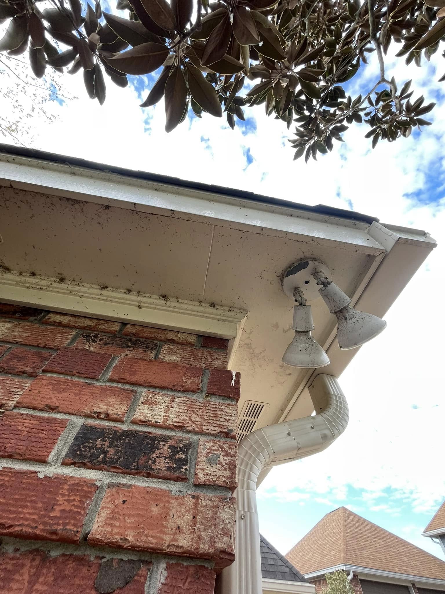 Mildewed fascia, dirty light fixtures, and stained brick before pressure washing