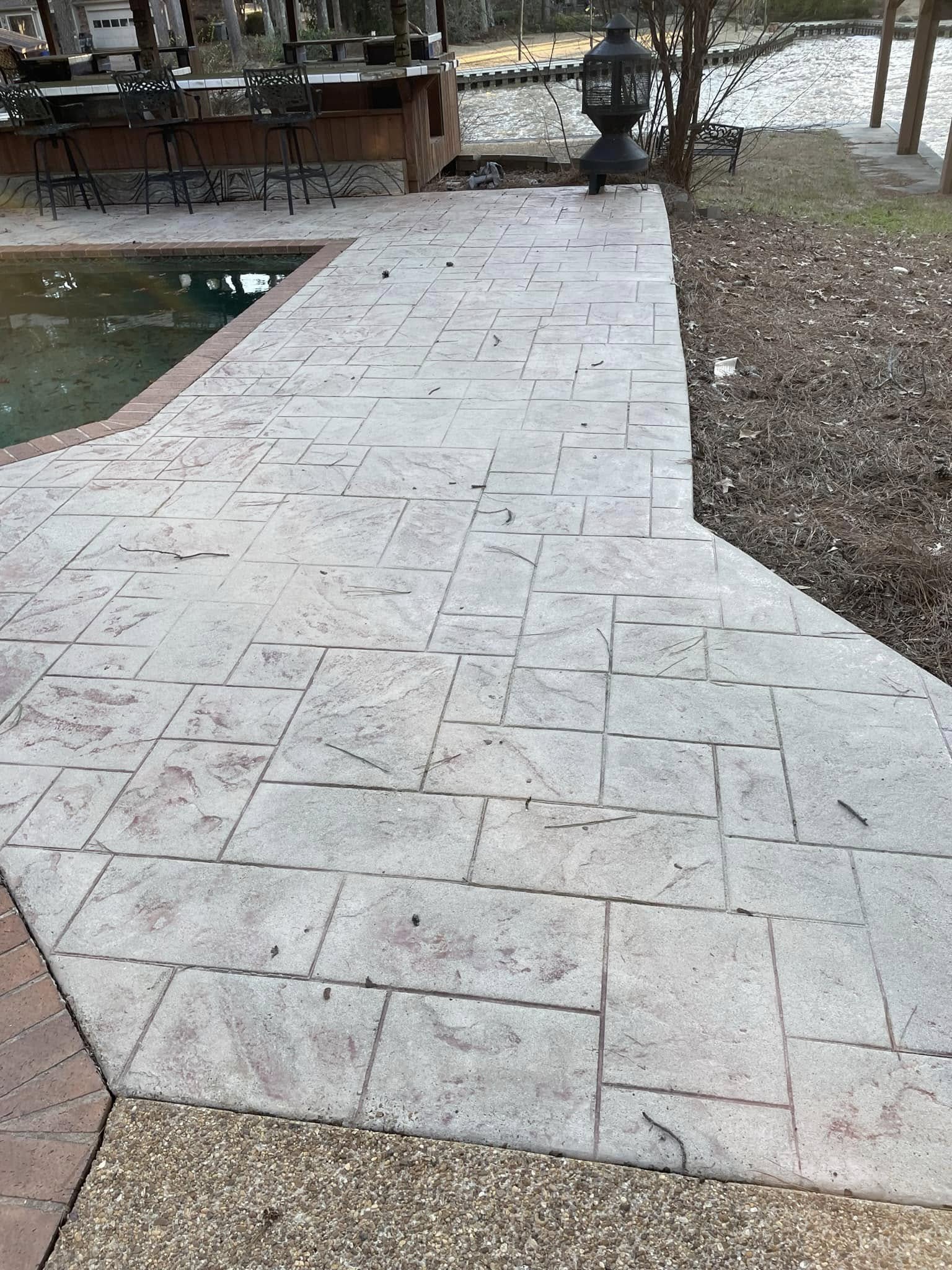 Same stamped concrete pool deck — clean and lifted after pressure washing